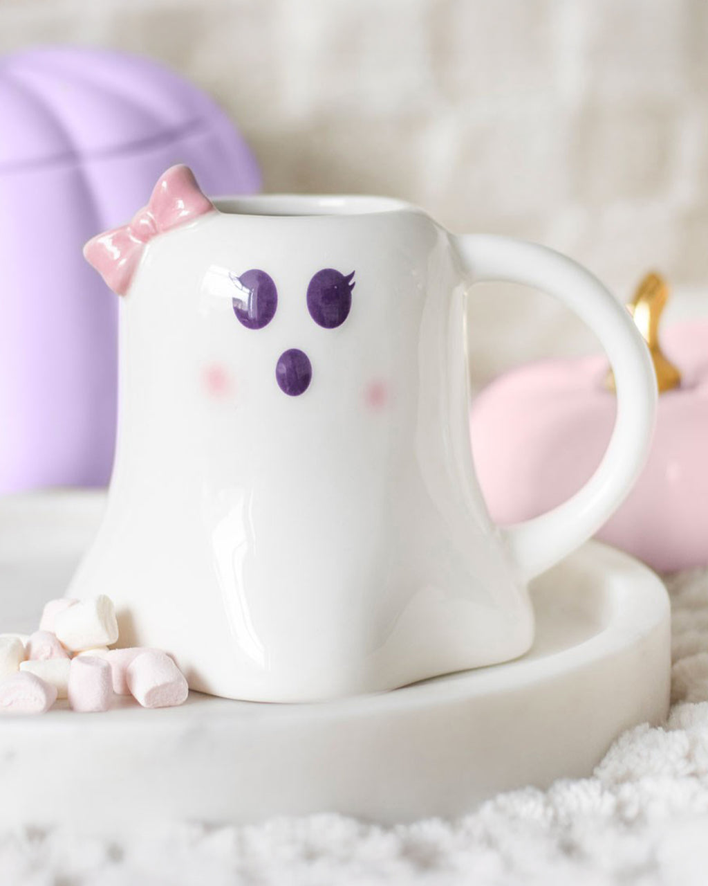 The Mrs Boo mug styled on a marble tray with marshmallows scattered around, purple and black decorative pumpkins in the background, creating a cosy Halloween aesthetic.