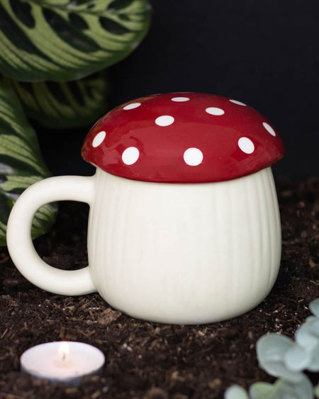 A cottagecore-inspired mushroom mug with a red polka dot lid, designed to resemble a whimsical toadstool. The cream-coloured ceramic base mimics a mushroom stem, creating a fairy-tale woodland aesthetic.