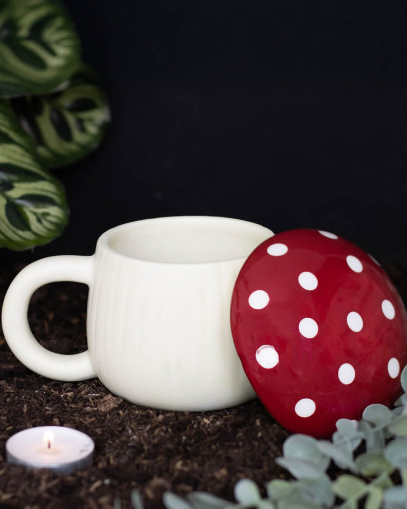 The mushroom-shaped coffee cup with its detachable toadstool lid placed beside it, revealing a spacious ceramic interior perfect for tea, coffee, or hot chocolate.