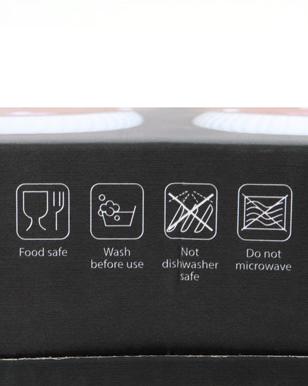 Close-up of icons on the packaging of the Mushroom Salt & Pepper Shaker Set by Rebel Romance, showing care instructions: food safe, wash before use, not dishwasher safe, and do not microwave.