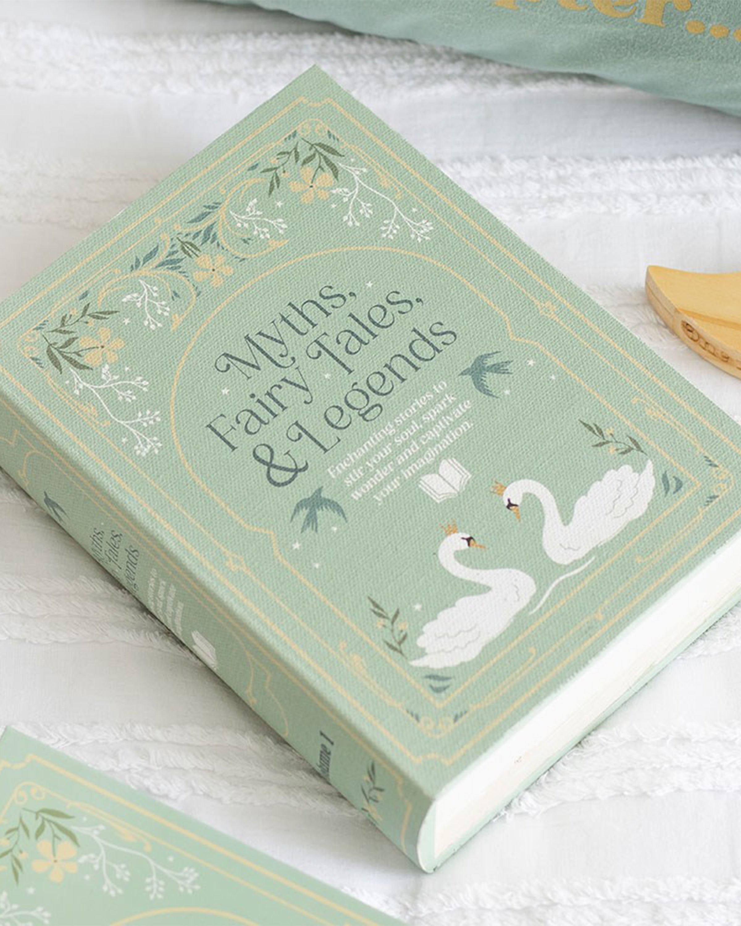 Flat lay of Rebel Romance Myths, Fairy Tales & Legends book shaped storage box in green with enchanting swan design and floral border. A magical hidden storage solution that looks like a vintage book, perfect for millennials who love whimsical and alternative home décor.