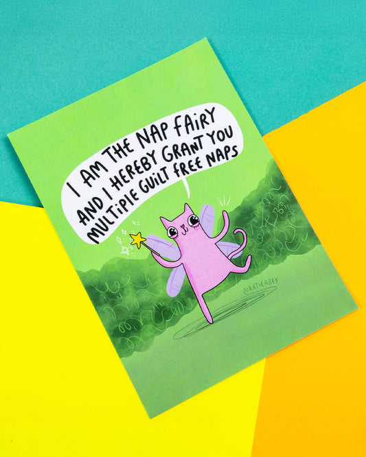 A green postcard of a cat with fairy wings and wand saying, I am the nap fairy and I hereby grant you multiple guilt free naps.