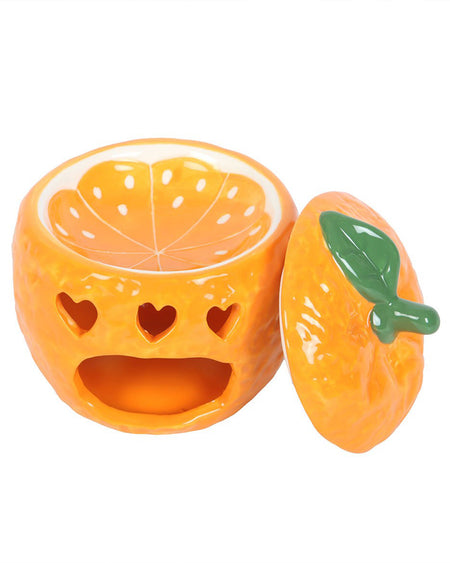 The orange oil burner with its lid off, displaying the inner dish designed to look like a juicy orange slice. The inner dish is ideal for holding wax melts or fragrance oils, making it a practical yet playful addition to any alternative or retro-inspired home aesthetic.