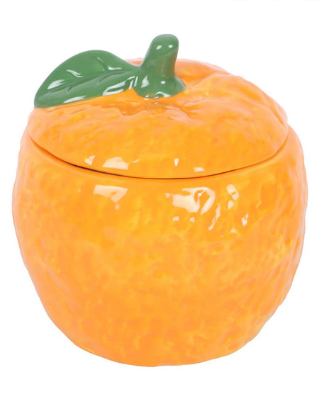 A ceramic oil burner shaped like an orange, complete with a textured peel effect and a green leaf on the lid. The lid is removable, revealing a dish inside for holding fragrance oils or wax melts. A stylish and functional home accessory from Rebel Romance, a UK-based alternative brand.