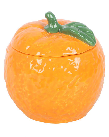 A front-facing view of the orange-shaped candle jar with the lid on. The ceramic jar mimics the look of a fresh orange, making it a fun and stylish home accessory.