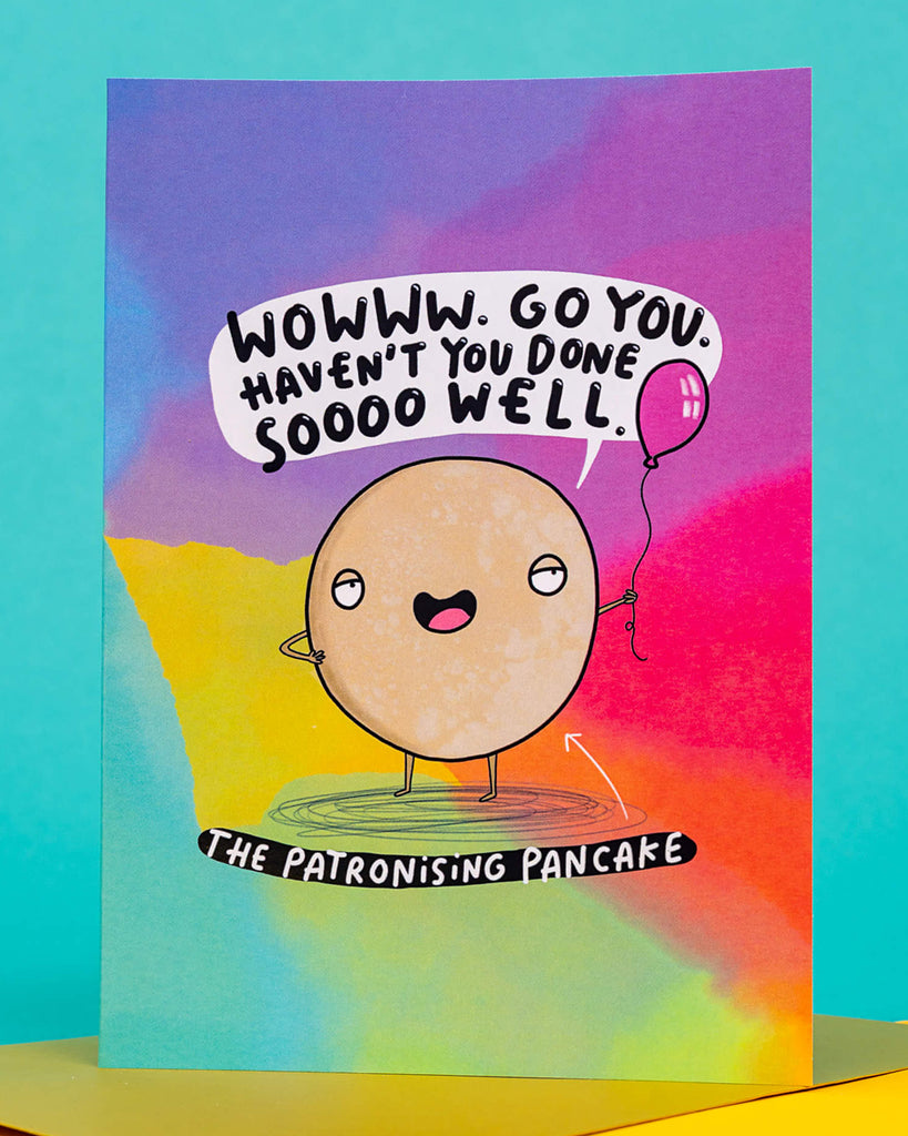 A colourful A6 greeting card from Rebel Romance featuring The Patronising Pancake character by Katie Abey. The pancake cartoon holds a balloon and says, “Wowww. Go you. Haven’t you done sooo well.” Set against a rainbow background, this sassy card is perfect for birthdays or cheeky celebrations. A fun, alternative card designed in the UK for millennials who love bold humour.