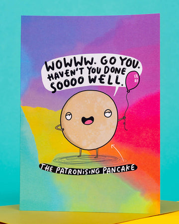 A colourful A6 greeting card from Rebel Romance featuring The Patronising Pancake character by Katie Abey. The pancake cartoon holds a balloon and says, “Wowww. Go you. Haven’t you done sooo well.” Set against a rainbow background, this sassy card is perfect for birthdays or cheeky celebrations. A fun, alternative card designed in the UK for millennials who love bold humour.