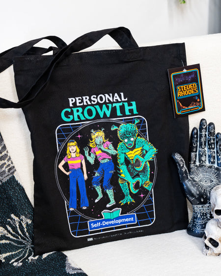 A black tote bag featuring Steven Rhodes’ “Personal Growth” design, showcasing a retro-inspired self-development illustration with vibrant neon colours and a humorous theme. The tote includes long handles for easy carrying and is labelled as officially licensed merchandise. Perfect for shopping, work, or travel.