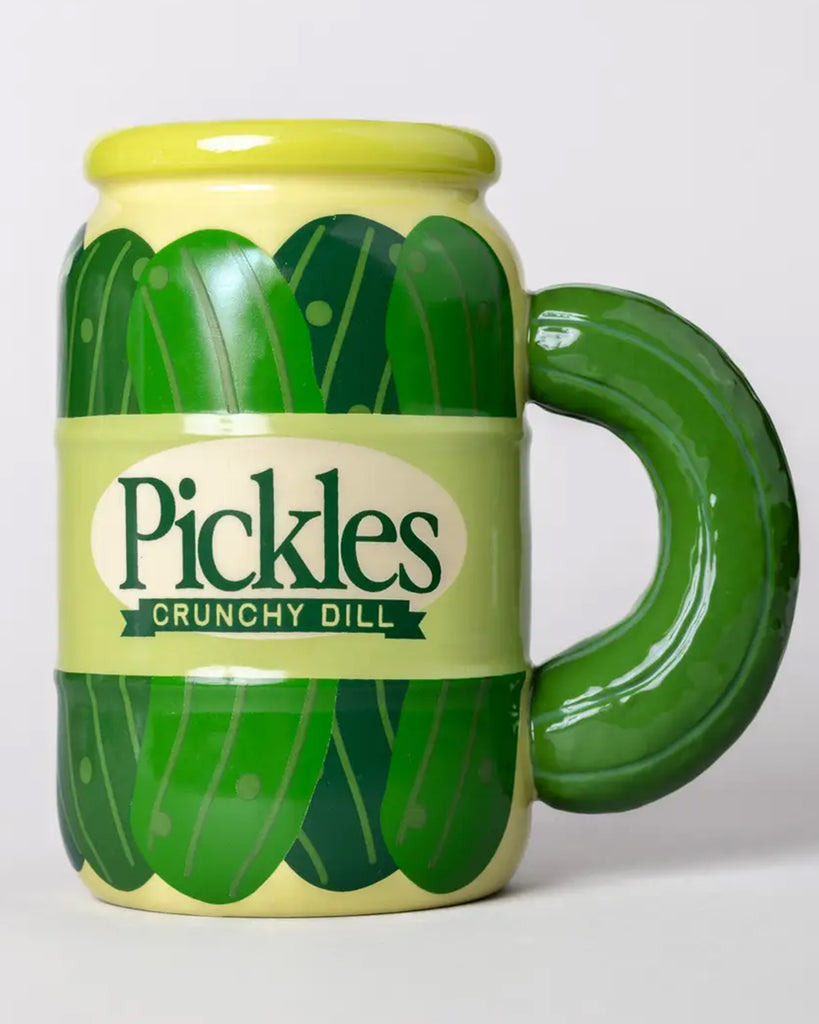 A quirky ceramic mug designed to look like a jar of crunchy dill pickles, sold by Rebel Romance. Features illustrated pickles wrapping around the body and a curved pickle handle.
