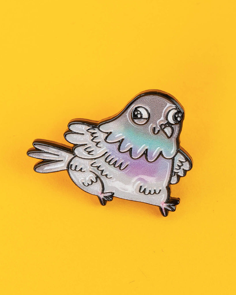 Straight-on view of the enamel pin badge showing the iridescent pastel pigeon design in full detail.