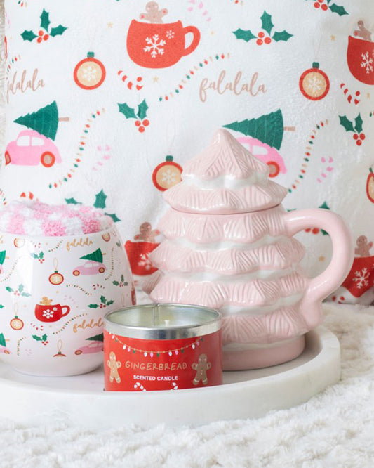 Cosy Christmas scene featuring the Rebel Romance Pink Christmas Tree Mug on a white tray, alongside a gingerbread-scented candle and festive mug. The background features a playful blanket with holly, baubles, and “falalala” print.