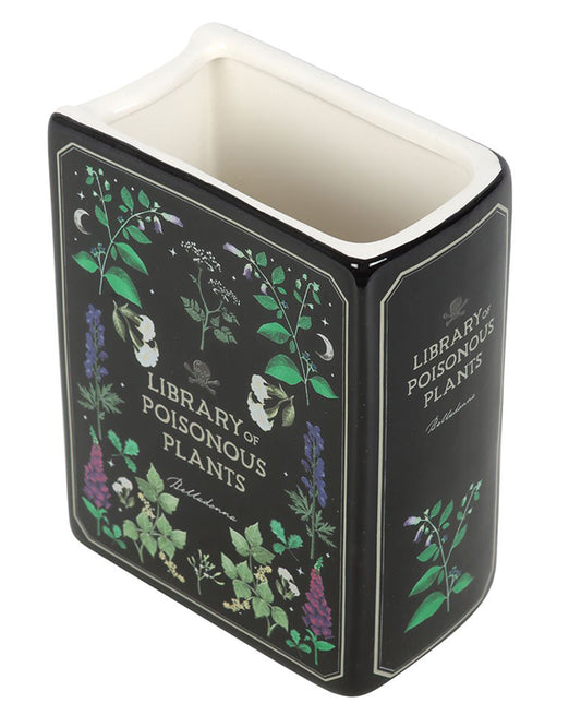 Ceramic book-shaped vase from Rebel Romance designed to resemble a vintage book titled "Library of Poisonous Plants". Features botanical illustrations on a black background with green, purple, and white floral detailing. Gothic homeware perfect for alternative decor lovers.
