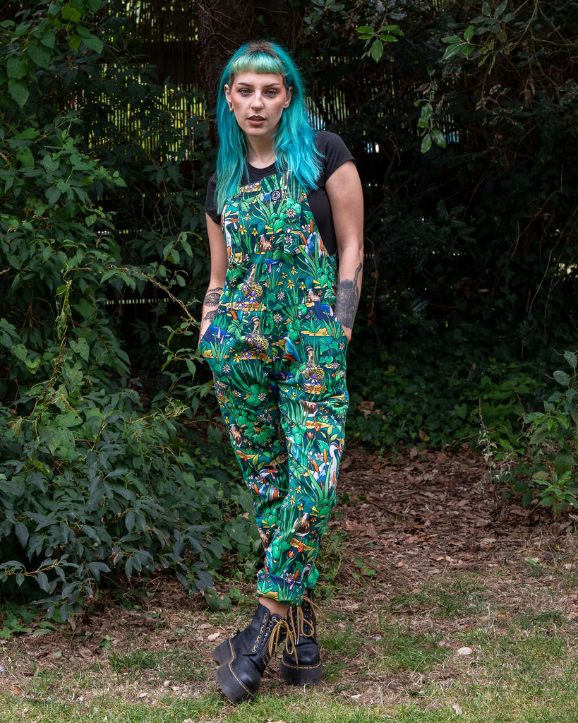 Claudia models the Rebel Romance Pond Birds Stretch Dungarees with a striking all-over pond life print of ducks, flowers, and greenery. Designed with comfy cotton twill, adjustable straps, and inclusive unisex fit, from 5XS to 6XL.