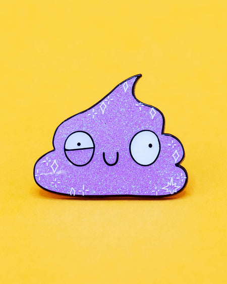 Close-up of a sparkly purple Galactic Poo enamel pin against a yellow background. The pin is shaped like a cartoon poo with a goofy, spacey expression and a glitter finish. Created by Katie Abey and sold by Rebel Romance, a UK indie brand specialising in quirky, uplifting, and weirdly wonderful accessories for millennial dopamine dressers.