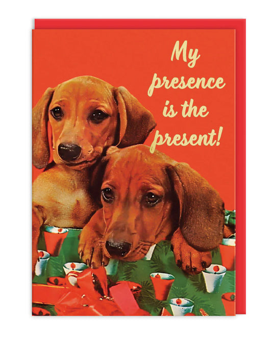 Retro-style sausage dog greeting card with two dachshund puppies sitting on festive wrapping paper and gifts, with the slogan "My presence is the present!" in gold foil. Designed by Ohh Deer, this A6 card from Rebel Romance is perfect for dog lovers and alternative gift-givers looking for a playful Christmas or birthday card. Comes with a brown kraft envelope and is blank inside for your message.