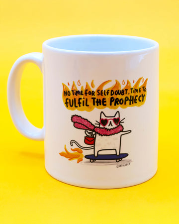 White ceramic mug with colourful illustration of a cat wearing heart sunglasses and a pink fluffy scarf, riding a skateboard through flames with the quote "No time for self doubt. Time to fulfil the prophecy" above in fiery text. Designed by Katie Abey, sold by Rebel Romance, a quirky UK alternative lifestyle brand.