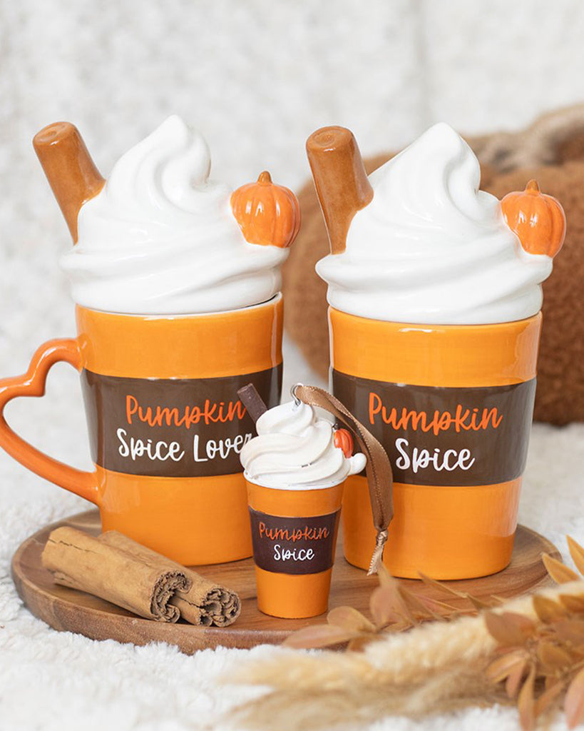 Ceramic pumpkin spice latte-shaped mugs from Rebel Romance with whipped cream lids, cinnamon stick details, and pumpkin decorations, styled in a cosy autumn setting. Includes a mini version with a ribbon. Ideal for alternative homeware fans and PSL lovers.