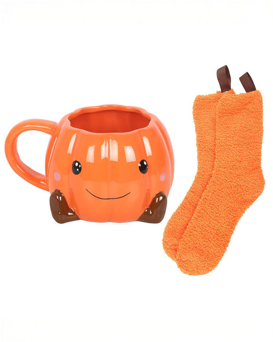 Rebel Romance ceramic pumpkin mug with a smiling face, shown alongside matching fluffy orange socks. A charming Halloween gift set ideal for cosy nights in, hot drinks, and autumn lovers. Great for gifting or keeping!