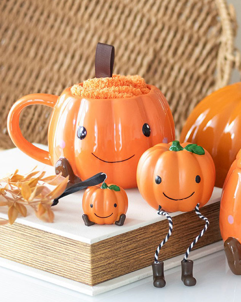 Cute Halloween-themed pumpkin mug and cosy orange socks from Rebel Romance, styled with mini pumpkin decorations and autumn leaves. A perfect autumnal gift set for spooky season lovers who enjoy hot chocolate in adorable ceramic mugs.