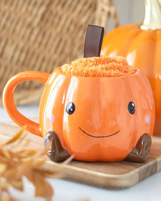 Rebel Romance pumpkin-shaped ceramic mug filled with orange fluffy socks styled on a wooden tray with cosy autumn decor. A cute and thoughtful Halloween gift idea with a playful seasonal twist.