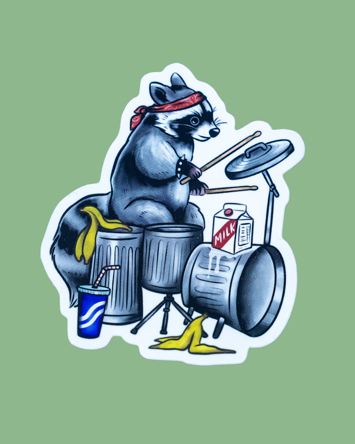 Vinyl sticker featuring a raccoon wearing a red bandana playing a drum kit made of silver dustbins, banana peels, a milk carton and a cup with a straw. Designed by MilkTeef for Rebel Romance.