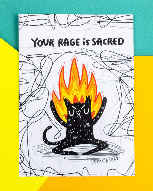 A postcard of an angry black cat on fire on a white background with back squiggles it has text above saying 'Your rage is sacred'. Illustrated by Katie Abey.