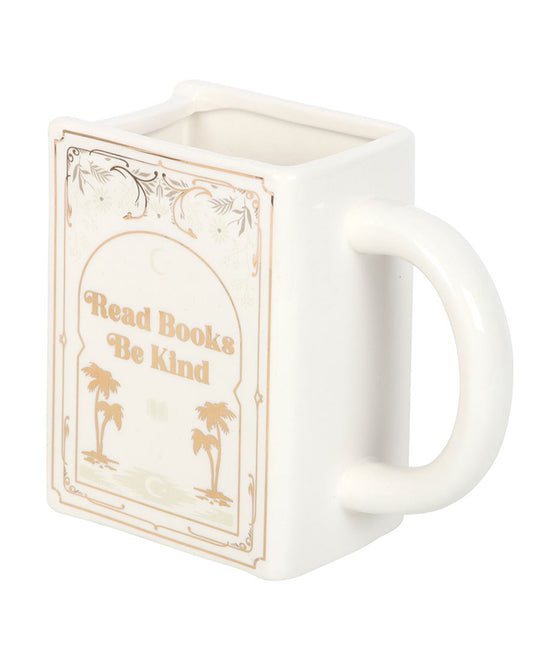 Close-up of the Rebel Romance Read Books Be Kind white ceramic mug, designed in the shape of a book with gold lettering and palm tree illustrations. A whimsical and unique gift for bookworms, tea lovers, and those who adore literary-themed homeware.