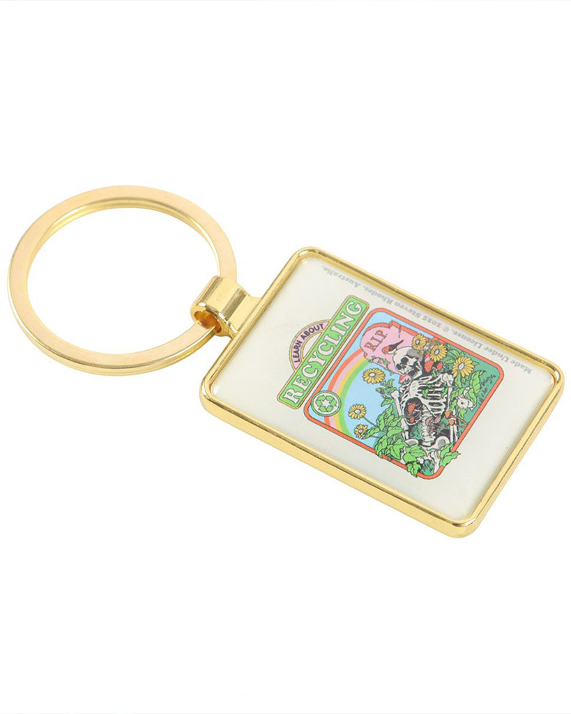 Side angle of the Rebel Romance enamel keyring featuring Steven Rhodes’ “Learn About Recycling” design. Gold rectangular keyring with colourful retro artwork of a skeleton in flowers and a rainbow graveyard scene. Perfect darkly comic eco gift for millennials who love quirky, alternative style.
