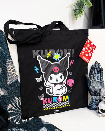 A black tote bag featuring Sanrio’s Kuromi in a colourful design with neon pink, blue, and yellow accents. The bag showcases Kuromi surrounded by lightning bolts, skulls, and fun punk-style details. Perfect for anime fans and alternative fashion lovers.