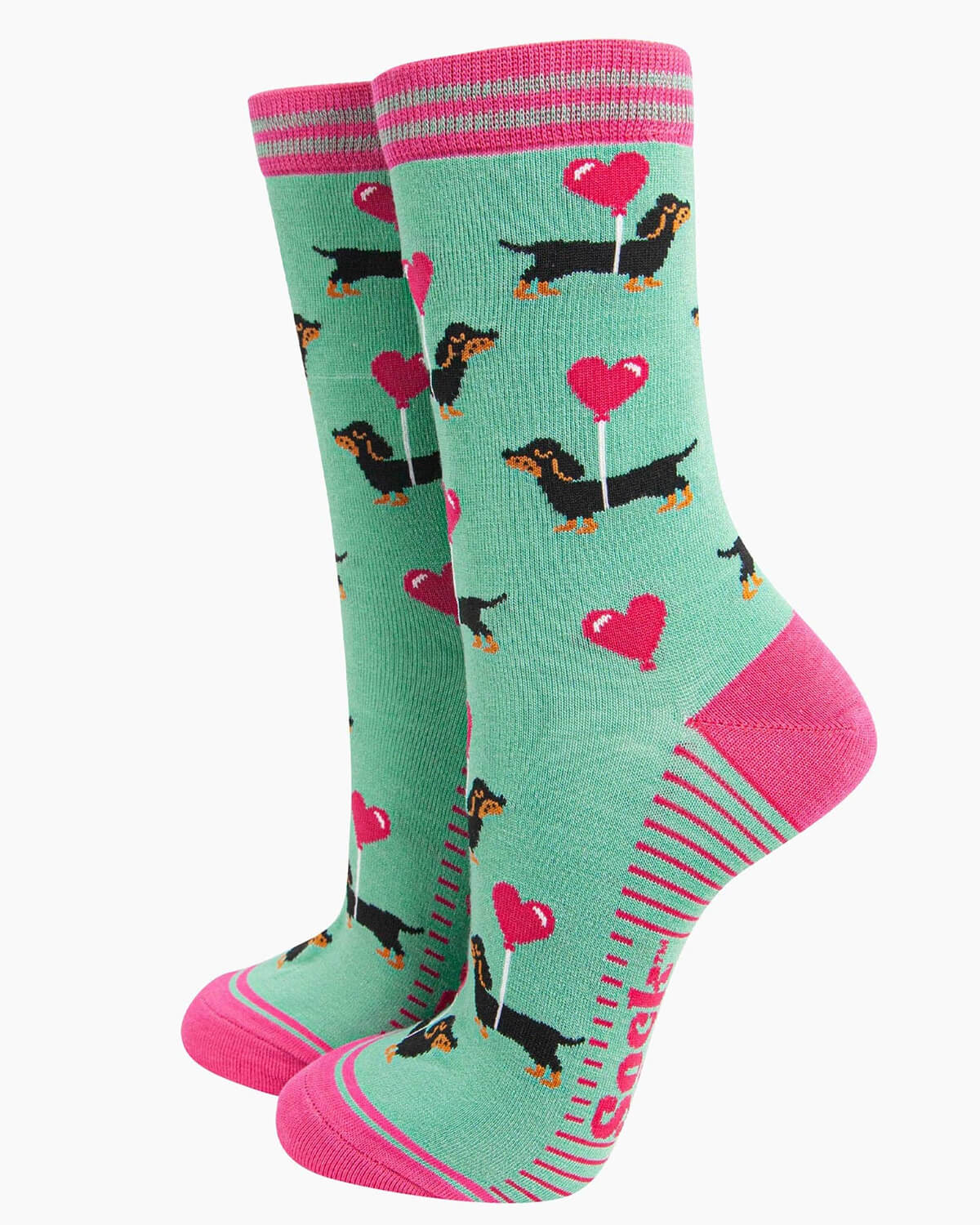 Flat lay of the socks, displaying their full design with striped pink cuffs and a playful sausage dog print.