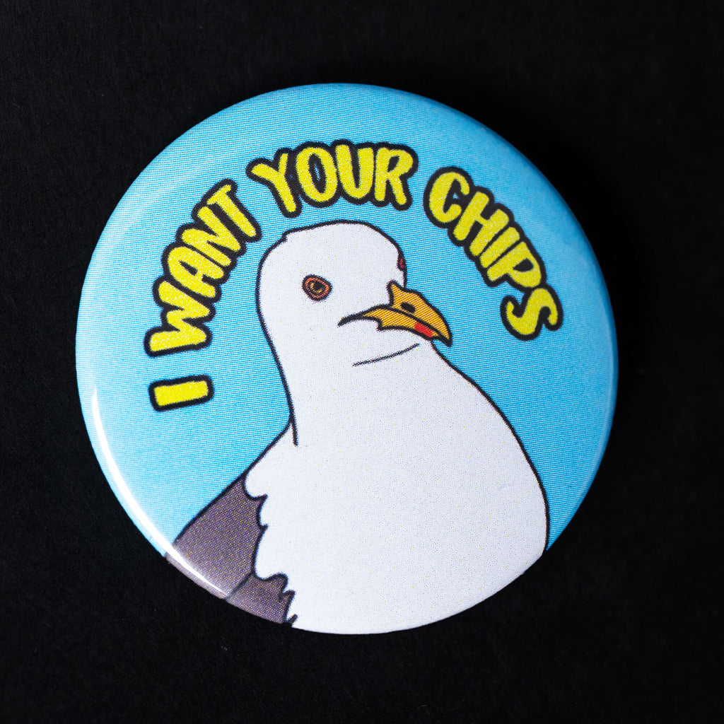 A 38mm glossy pin badge featuring a cheeky illustrated seagull on a bright blue background with bold yellow text that reads “I Want Your Chips.” A humorous and playful accessory celebrating British seaside culture.