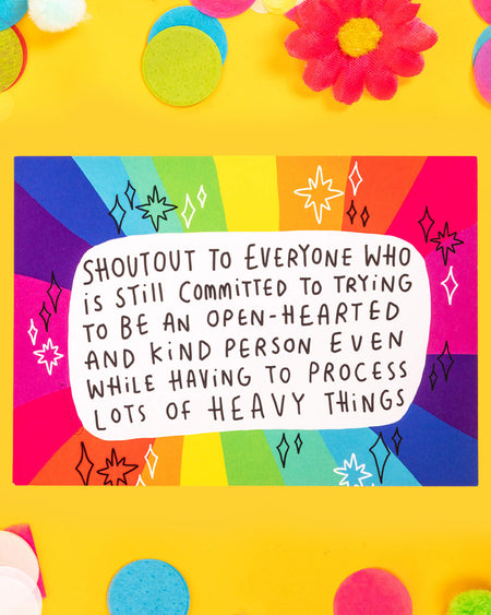 A colourful A6 postcard designed by Katie Abey with a rainbow background and black-and-white text that reads: “Shoutout to everyone who is still committed to trying to be an open-hearted and kind person even while having to process lots of heavy things.” The perfect uplifting message of emotional strength and kindness.