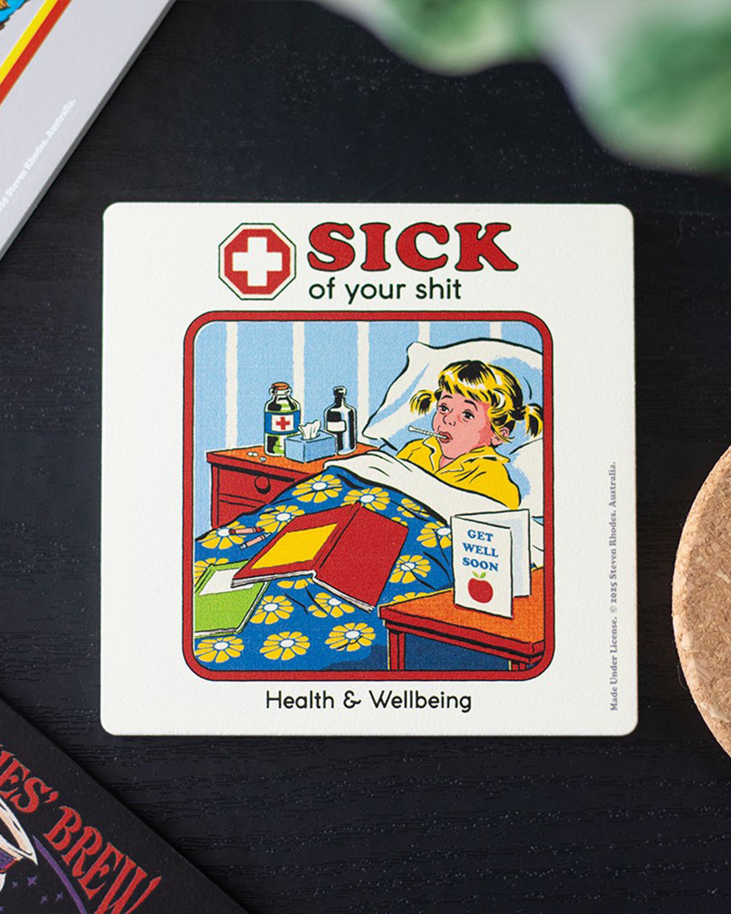Steven Rhodes “Sick of Your Shit” coaster styled on a dark tabletop. Retro humour homeware gift available at Rebel Romance, perfect for protecting surfaces while adding quirky alternative style to your space.