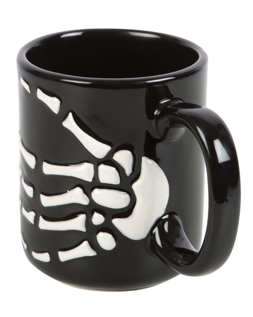 Side angle of the Skeleton Hand Mug with handle, displaying the raised bone details in white on the black ceramic surface.