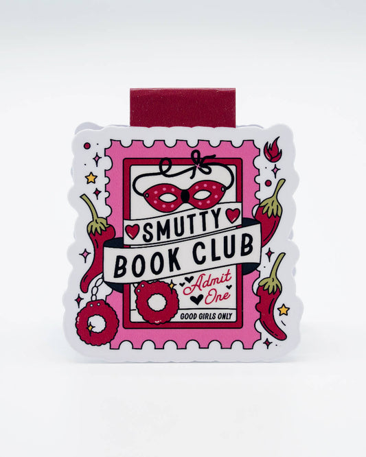 Front view of the Smutty Book Club Magnetic Bookmark from Rebel Romance, shaped like a raunchy pink ticket with illustrations of a mask, handcuffs, chillies, and hearts. Features the slogan “Good Girls Only” and “Admit One.” A fun and flirty gift for fans of steamy fiction and those who love to spice up their reading time with alternative accessories.