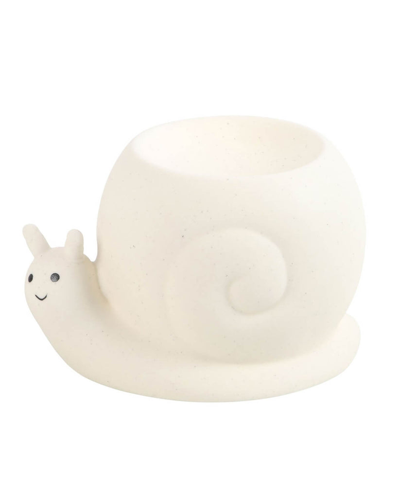 A close-up of a ceramic snail-shaped oil burner with a soft, speckled finish. The snail has a cute, smiling face, and the round shell serves as the oil dish. Designed by Rebel Romance, this alternative homeware piece brings a blend of minimalist charm and quirky aesthetics, ideal for those who love unique and unusual decor.