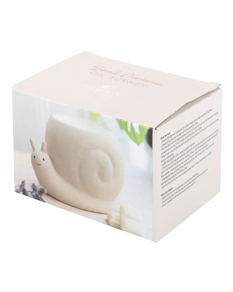 A cute ceramic snail-shaped oil burner in its branded packaging from Rebel Romance, a UK-based alternative lifestyle brand. The box features an image of the oil burner with a soft, neutral aesthetic, alongside lavender and wax melts. The text on the packaging highlights its function as an oil burner and adds a whimsical touch to home decor. Perfect for millennials who love unique and quirky homeware.