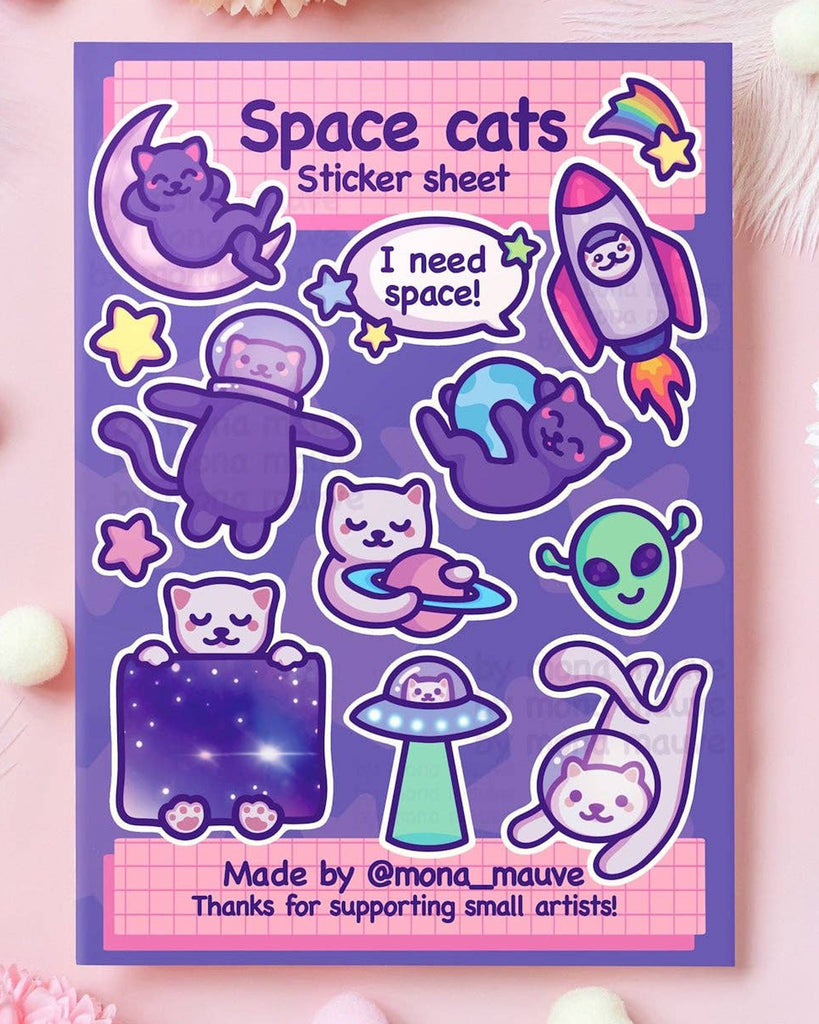 Space Cats sticker sheet with 13 cute waterproof vinyl stickers featuring cosmic cats in astronaut helmets, rockets, UFOs, and galaxies. Includes playful phrases like “I need space” and adorable alien and planet elements. Designed by Mona Mauve and sold by Rebel Romance, a small UK business that celebrates queer joy, creativity, and alternative art.