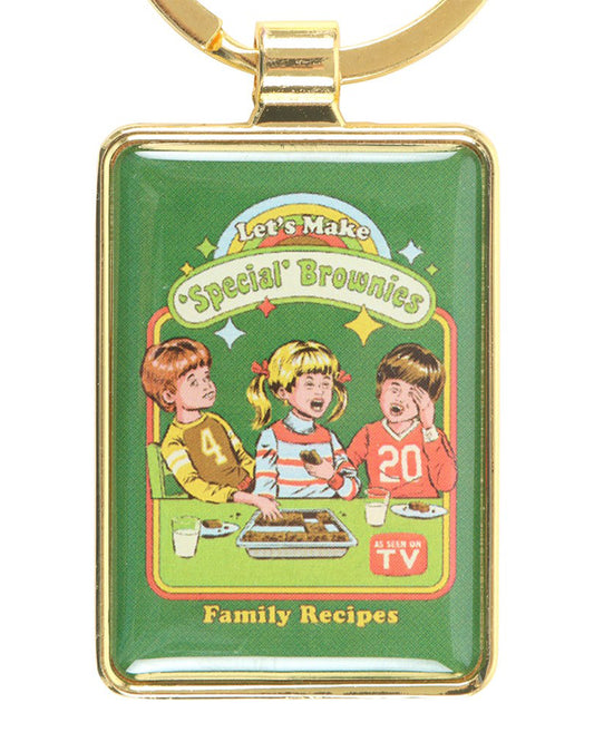 Rebel Romance Let's Make 'Special' Brownies keyring by Steven Rhodes. Retro enamel keychain featuring a vintage-style illustration of children baking, with a cheeky nod to herbal brownies. Quirky alternative accessory for millennials who love unique gifts, humour, and retro pop culture design.