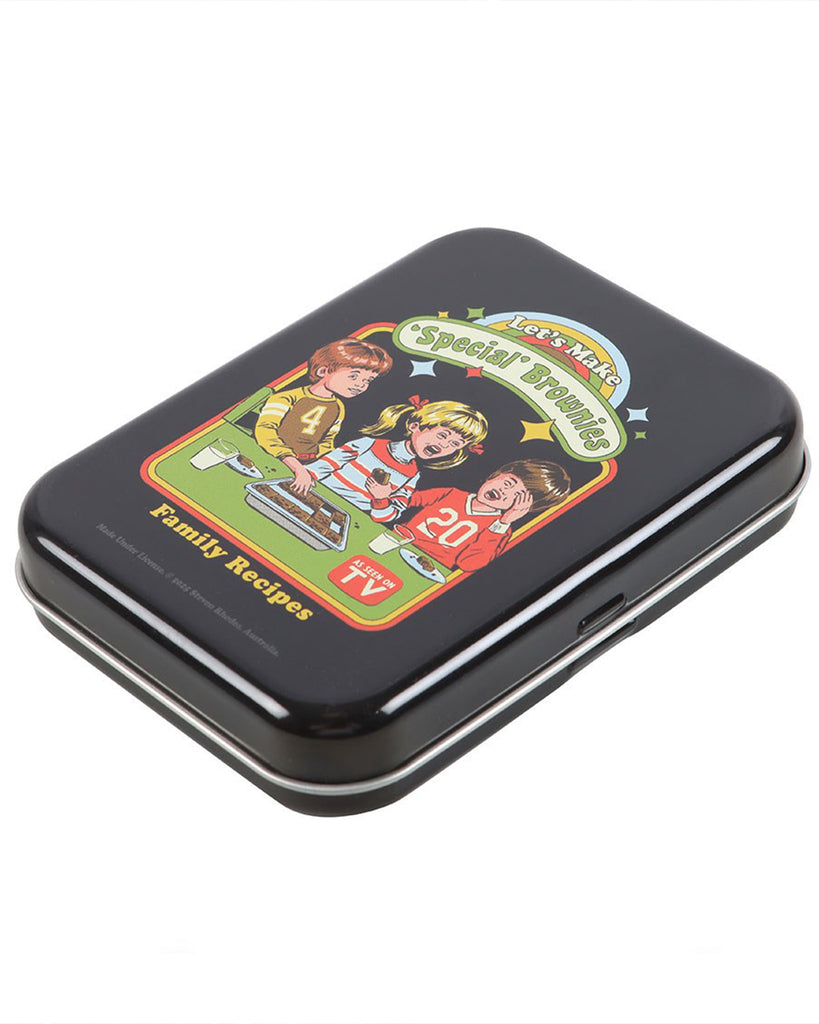 Angled view of the Rebel Romance “Let’s Make Special Brownies” stash tin designed by Steven Rhodes. This retro metal storage tin features cheeky vintage-style artwork with children making special brownies, blending nostalgic design with dark humour. A fun alternative homeware gift for quirky millennials.
