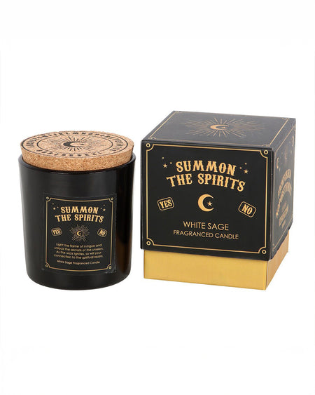 A black glass candle jar with gold mystical spirit board-inspired details and a cork lid, next to a matching black and gold box that reads "Summon the Spirits" and "White Sage Fragranced Candle." The candle is from Rebel Romance, a UK brand celebrating alternative fashion and aesthetics.