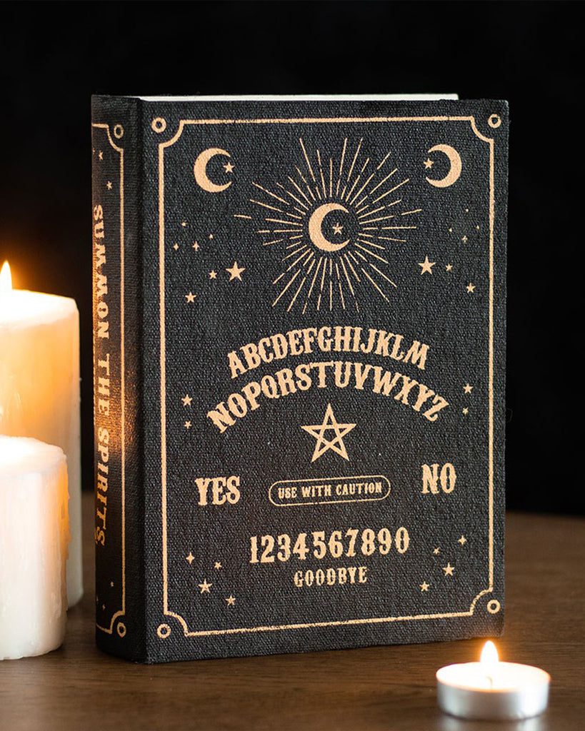 The Black Talking Board Book Storage Box by Rebel Romance displayed with lit candles for a moody, gothic aesthetic. The black and gold talking board design stands out, making it both a stylish décor piece and a functional storage solution.