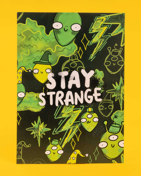 A dark green and neon A6 postcard featuring a group of quirky green aliens, stars, and lightning bolts with the bold text “Stay Strange” in white. Designed by Katie Abey, this playful and eccentric card is ideal for millennials into alternative humour, quirky stationery, and embracing their inner weirdo.