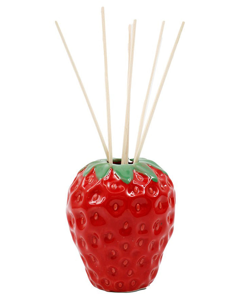 The Strawberry Fields Reed Diffuser from the cottagecore stockist, Rebel Romance, featuring a glossy red ceramic strawberry vase with realistic seed detailing and green leaves. Six natural reed sticks extend from the top, diffusing a sweet strawberry scent into the air.