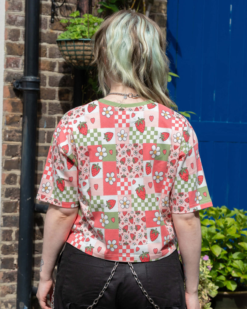 Back view of the Rebel Romance Strawberry Picnic Cropped Tee showing the colourful patchwork print with strawberries, daisies, and hearts on pink, red, and green blocks.