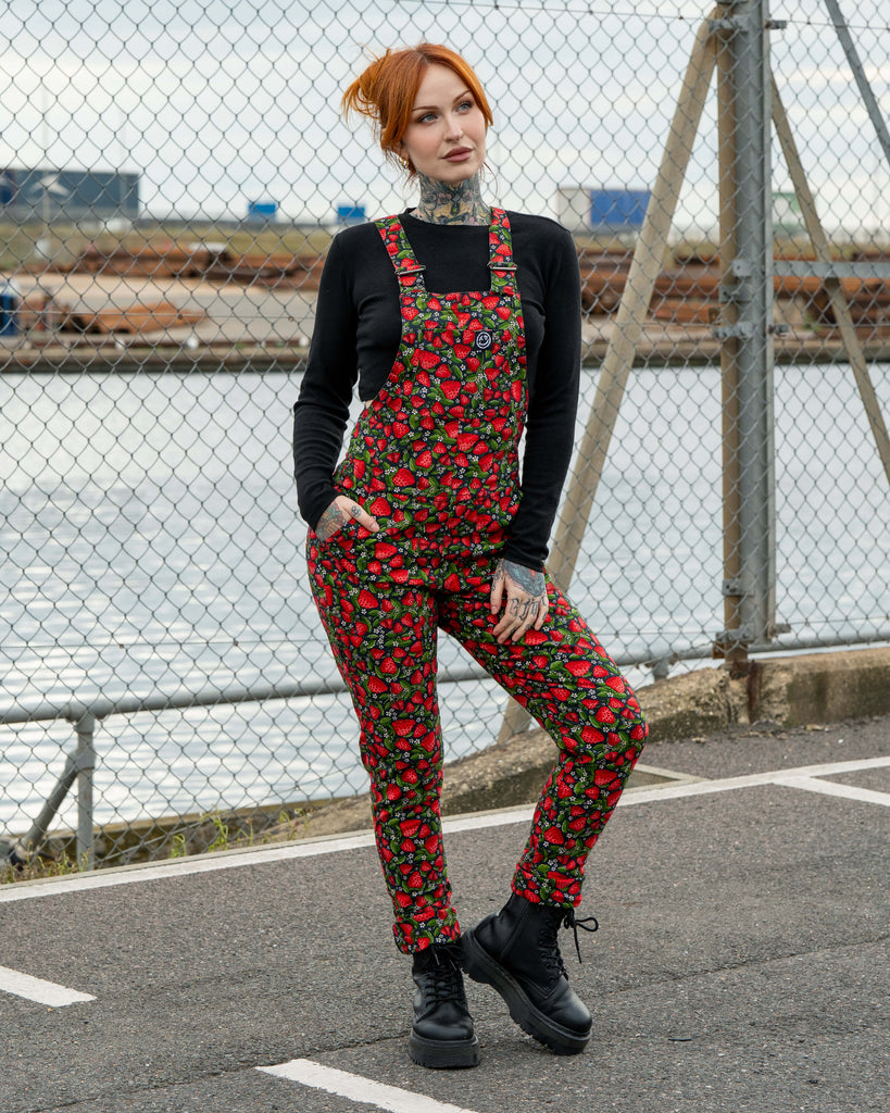 Erin poses in Rebel Romance Strawberry Field stretch twill dungarees with a bold red strawberry print. A fun dopamine dressing look for alternative and retro fashion lovers.