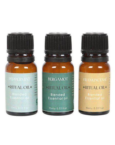 Three amber glass bottles of Success Ritual essential oils, labeled Peppermint, Bergamot, and Frankincense, with pastel green, teal, and beige labels, standing upright in a row.