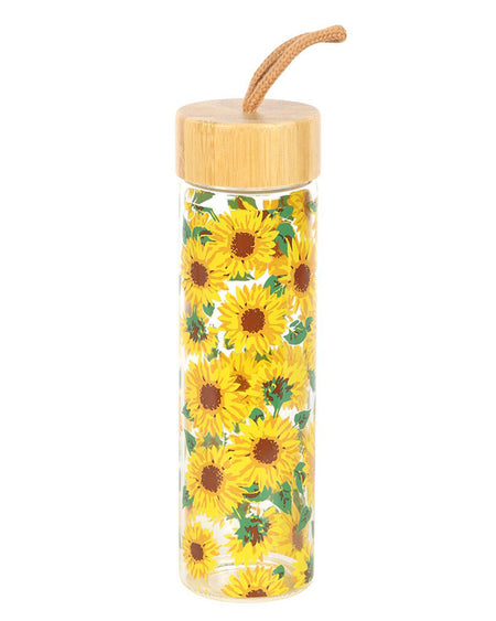 Close-up of the Rebel Romance sunflower glass water bottle. The tall, clear bottle is covered in bright yellow sunflowers with green leaves, topped with a bamboo lid and a tan cord loop. This 600ml eco-friendly bottle is perfect for staying hydrated while embracing your quirky, retro aesthetic.