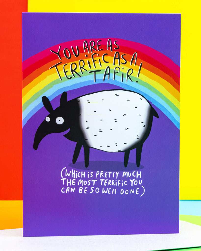 A6 greeting card by Rebel Romance featuring a cute illustrated tapir by Katie Abey on a purple background with a vibrant rainbow. The text reads “You are as terrific as a tapir! (Which is pretty much the most terrific you can be so well done)”. A fun and uplifting card, perfect for celebrations or random acts of kindness. Designed in the UK and printed on 250gsm card. Great for millennial gift-givers who love quirky and colourful designs.