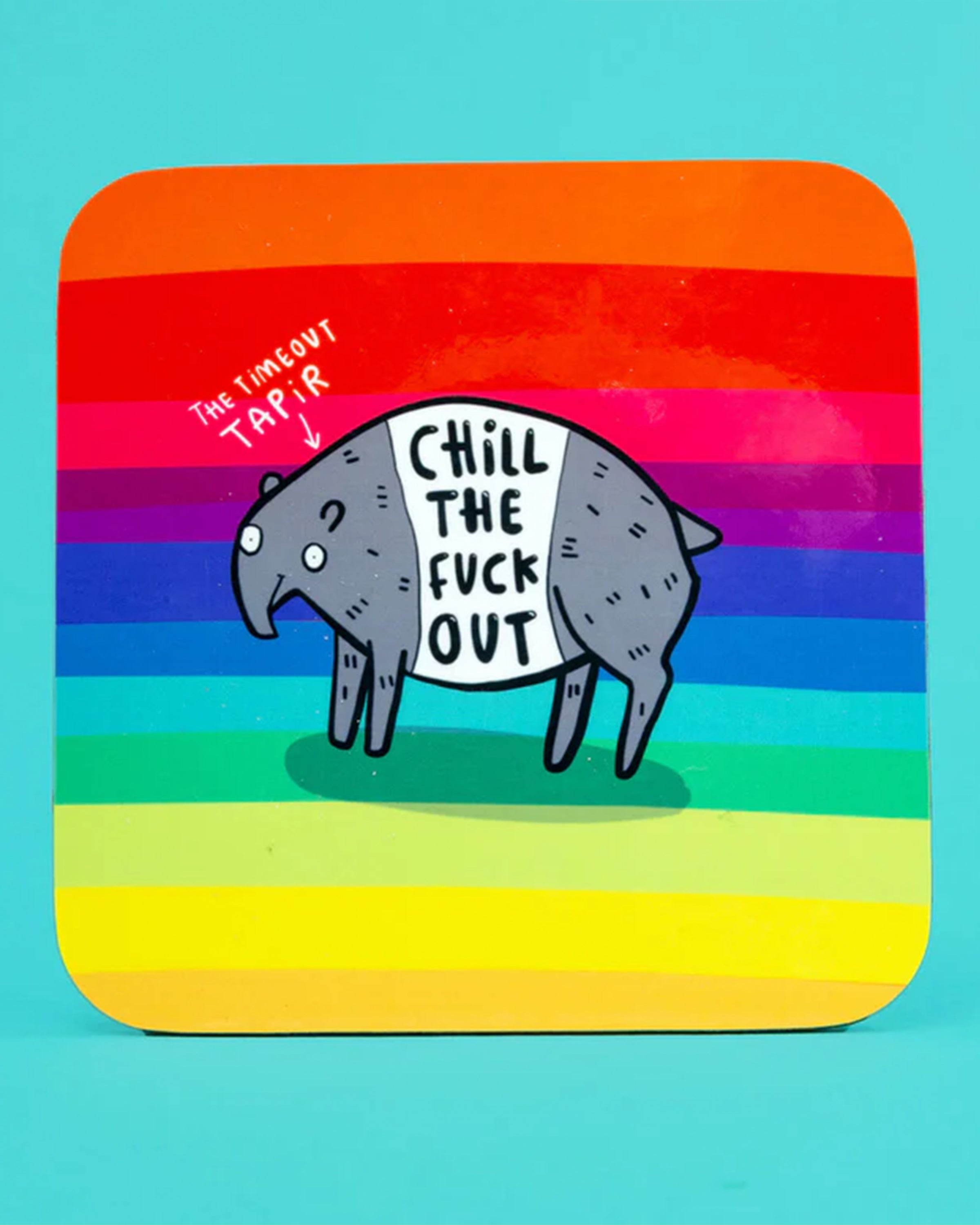 The Katie Abey “Chill The Fuck Out” coaster on a bright yellow surface beside a mug and biscuits. The rainbow striped design with a funny illustrated tapir makes this Rebel Romance homeware piece a playful and uplifting gift.